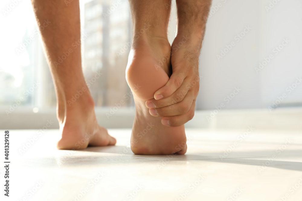 Back view of man suffering from foot pain indoors, closeup. Space for text Back view of man suffering from foot pain indoors, closeup. Space for text