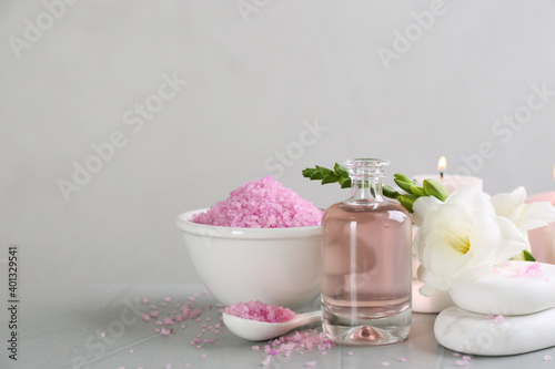 Beautiful composition with spa stones and essential oil on light grey table, space for text