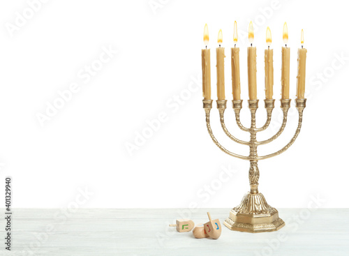 Golden menorah and Hanukkah dreidels with He, Gimel, Nun symbols on white background