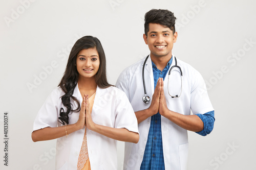 Photography Indian young male and female doctor greeting namaste against white
