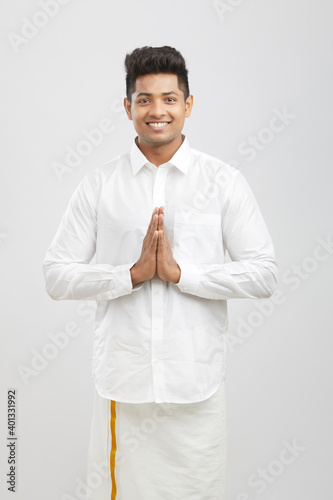 Portrait young happy south Indian man greeting in traditional dress.