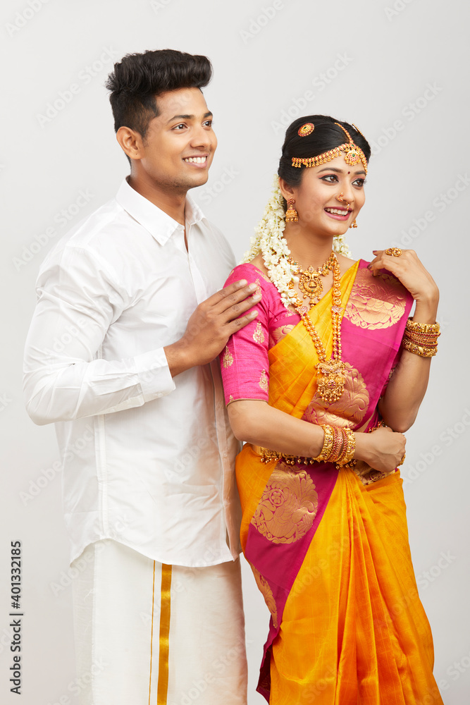 Attractive happy south Indian couple in traditional dress on white.