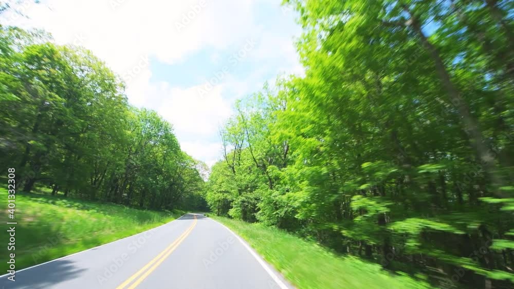 Point of view pov handheld front view of car driving on Shenandoah Skyline Drive winding road by park mountain forest in summer with green foliage trees