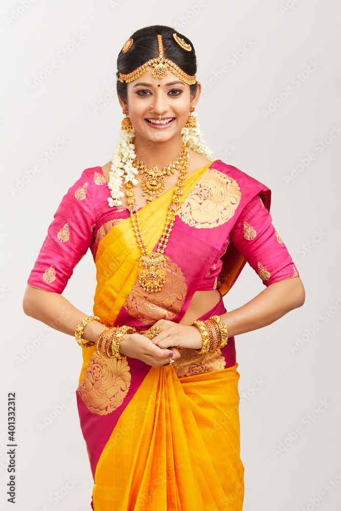 Beautiful smiling Indian bride posing with jewelry against white.