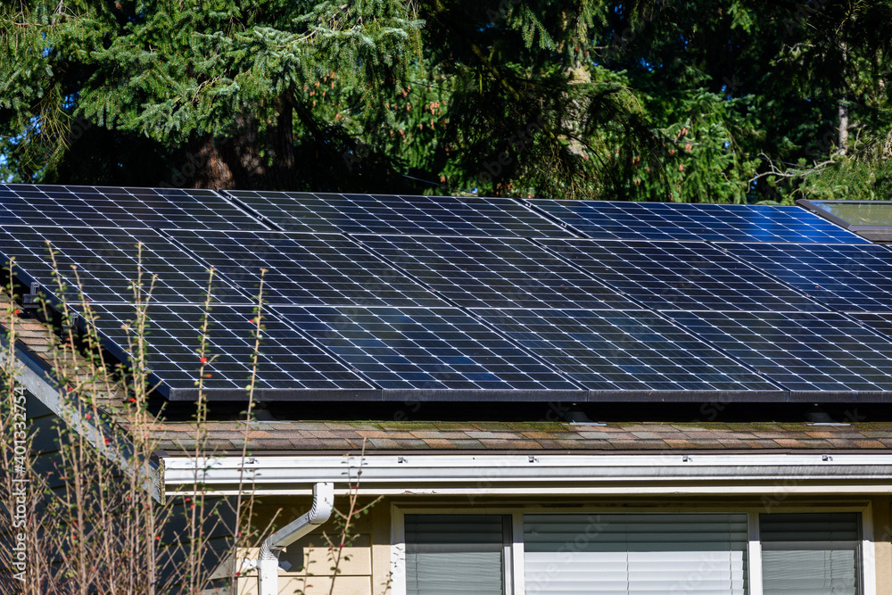 Residential house roof covered in solar panels for green energy generation, sunny day
