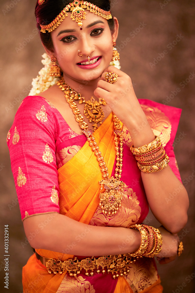 Obraz premium Beautiful smiling Indian bride with jewelry in studio shot.