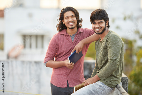 Happy young people chatting with book on terrace.