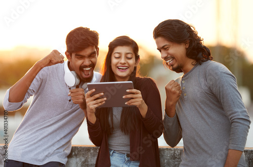 Excited of friends watching tv from tablet at outdoor background. photo