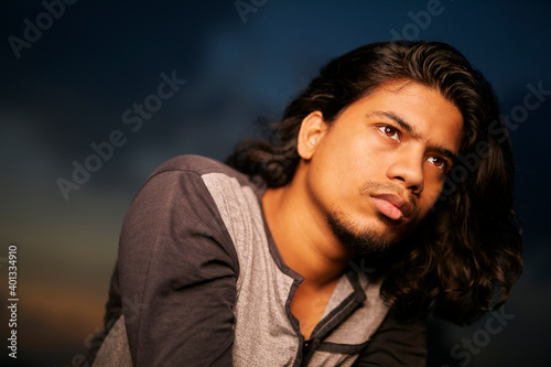 Young man portrait with long hair in evening light