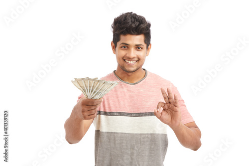 Attractive young Indian cheering with Indian rupees on white.