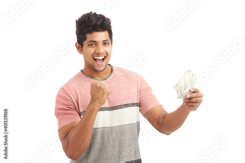 Attractive young Indian cheering with Indian rupees on white.