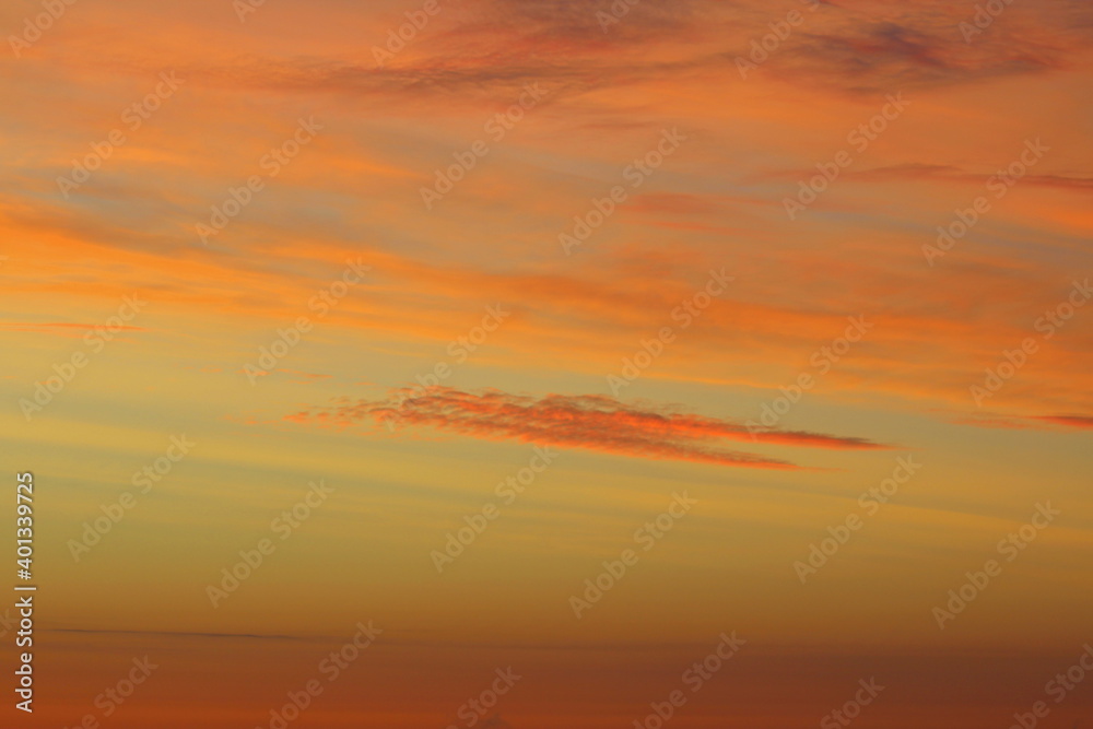 Obraz premium Sun below the horizon and clouds in the fiery dramatic orange sky at sunset or dawn backlit by the sun. Place for text and design