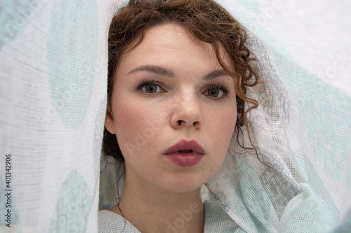 A beautiful young woman in a white veil resembling a bride's veil