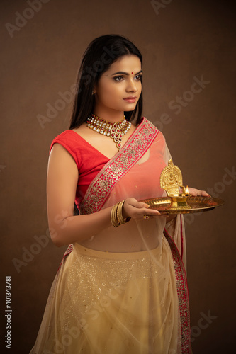 Hindu Indian young women holding Deepam in hands studio shot. ( Kamatchi vilakku ) photo