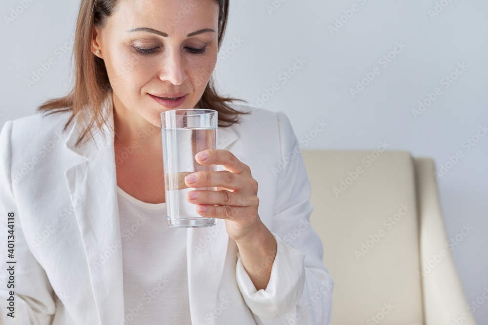 Mature business woman drinks water, close-up of female face and glass of water Mature business woman drinks water, close-up of female face and glass of water