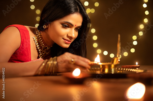 Canvas Print Beautiful Hindu Indian young women lightening Diya on Diwali day.