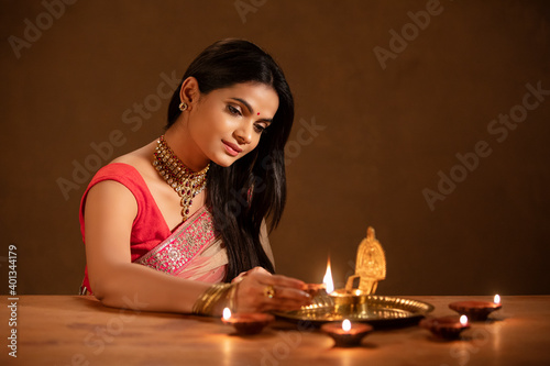 Photography Beautiful Hindu Indian young women lightening Diya on Diwali day.