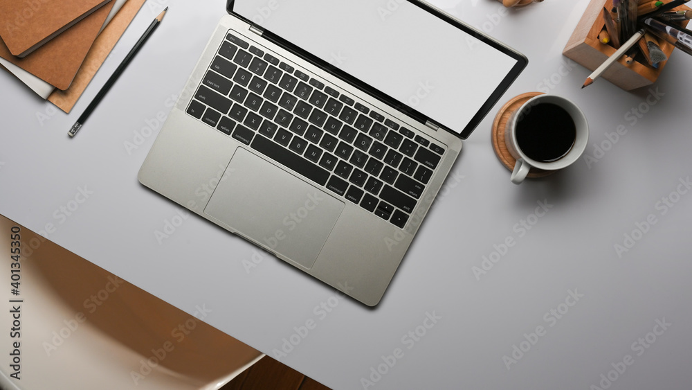 Worktable with laptop, coffee up and stationery in home office room Worktable with laptop, coffee up and stationery in home office room