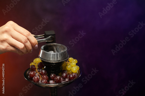 Woman putting coal cubes on tobacco bowl, closeup