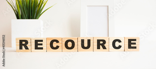 Wooden cubes with letters on a white table. The word is RECOURCE. White background.