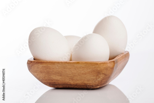 Wooden cup of white eggs on white background.
