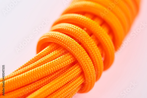 Close-up on a coil of orange paracord on white background photo