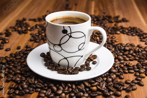 Cup of coffee with coffee beans at wooden background.