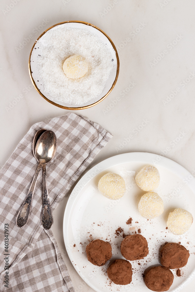 Homemade Indian round vegetarian sweets. Coconut and cocoa balls in a white bowl with coconut shavings Homemade Indian round vegetarian sweets. Coconut and cocoa balls in a white bowl with coconut shavings
