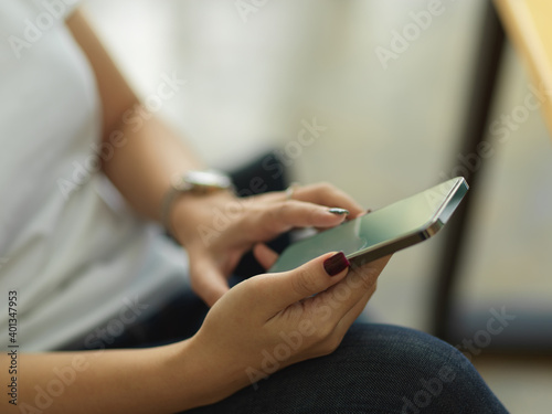 Female hands using smartphone while sitting in home office room