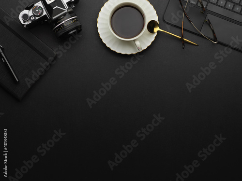Top view of copy space on black table with coffee cup, camera and supplies
