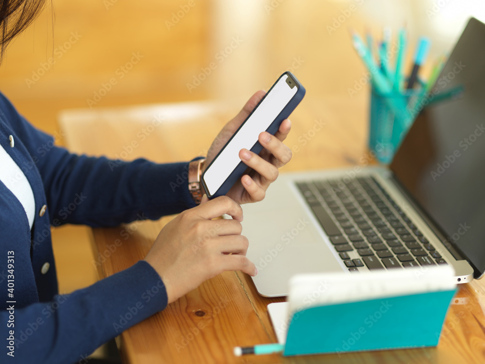 Fototapeta premium Businesswoman using smartphone while working with laptop and stationery