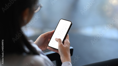 Close up view of young female relaxing at her workplace and using smart phone.