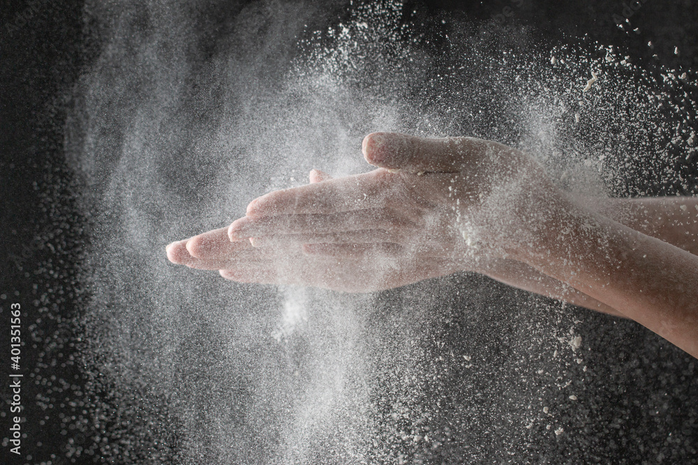 wave of hands with flour on a black background