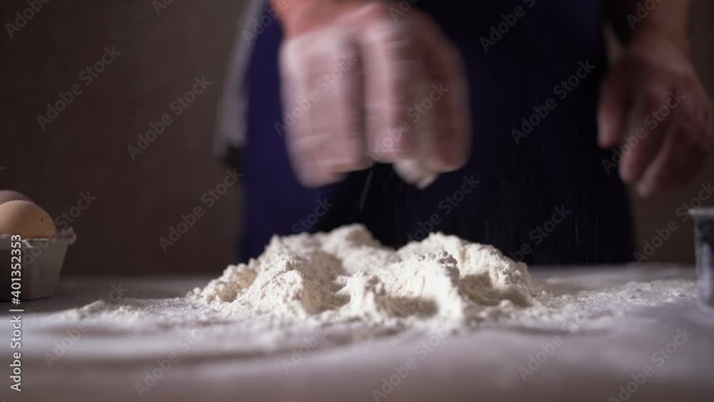 A professional pastry chef sprinkles flour on the table. Concept: production of sweets, pies, dough, pizza, delicacy, pure product, baking, working in restaurants, baking A professional pastry chef sprinkles flour on the table. Concept: production of sweets, pies, dough, pizza, delicacy, pure product, baking, working in restaurants, baking