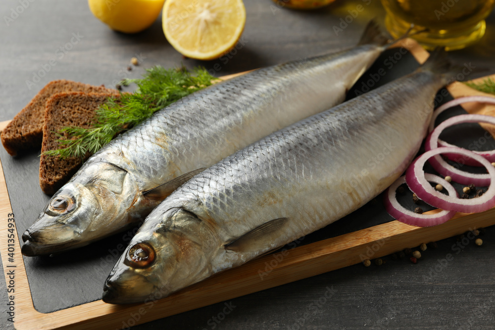 Board with herring fish and spices, and oil on dark wooden background Board with herring fish and spices, and oil on dark wooden background
