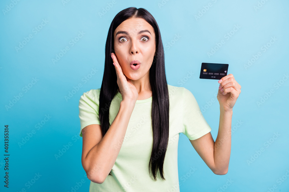 Portrait of charming amazed cheerful girl holding in hands plastic card wow pout lips isolated over bright blue color background Portrait of charming amazed cheerful girl holding in hands plastic card wow pout lips isolated over bright blue color background