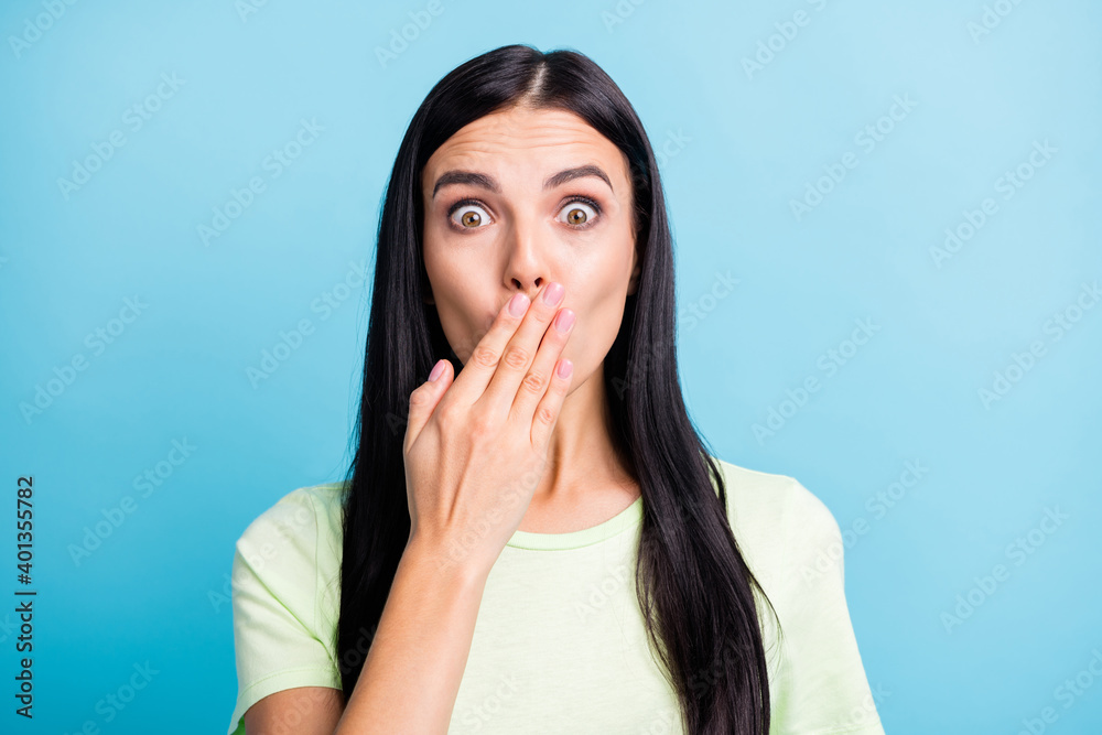Photo portrait of shocked girl closing mouth with one hand isolated on pastel blue colored background Photo portrait of shocked girl closing mouth with one hand isolated on pastel blue colored background