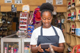 female african shop attendant smiling while using a calculator