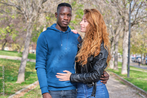 African black man and redhead caucasian woman smiling in a park. Young multiracial couple portrait.