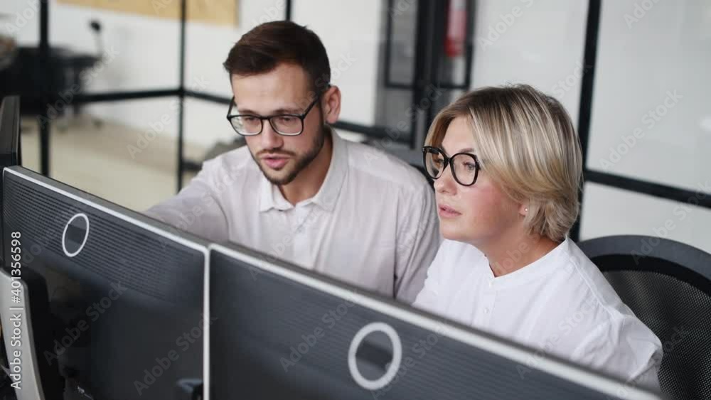 Male and female stockbrokers in formal clothes works in the office by computers and analyzing data. Male and female stockbrokers in formal clothes works in the office by computers and analyzing data.