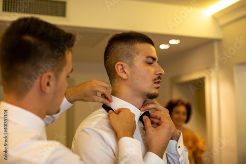 groomsmen help groom to fixing his bow
