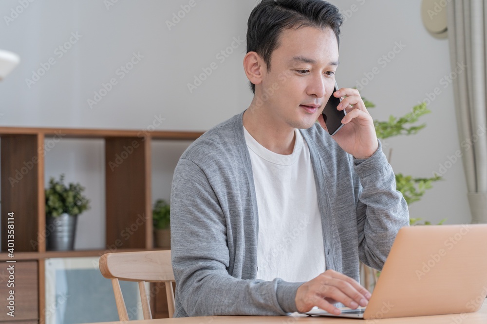 パソコンと携帯を使用して会議をするアジア人 パソコンと携帯を使用して会議をするアジア人