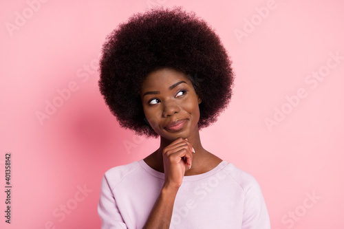 Portrait of pretty cheery minded brainy wavy-haired girl touching chin creating solution isolated over pink pastel color background