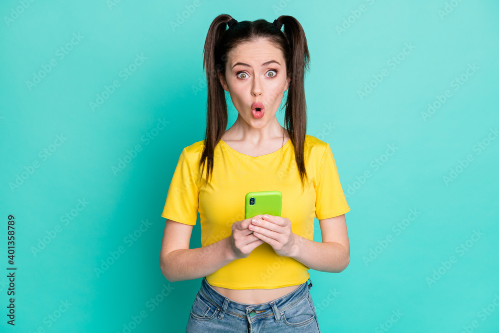 Portrait of impressed brunette girl hold telephone wear t-shirt isolated on blue color background Portrait of impressed brunette girl hold telephone wear t-shirt isolated on blue color background