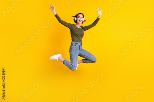 Full body photo of girl jump listen music wireless headset wear sweater isolated on bright yellow color background