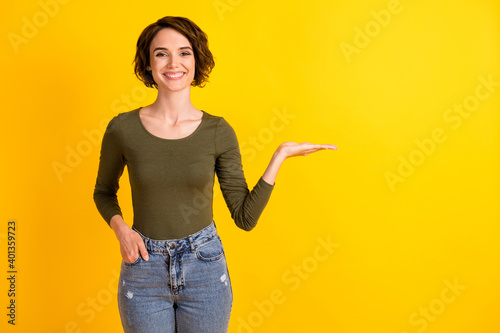 Photo of positive lady hold hand empty space for sale adverts promotion isolated over bright yellow color background