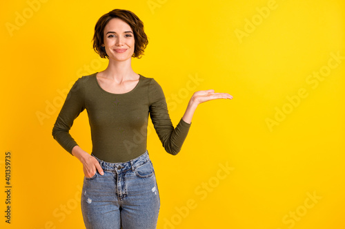 Photo of positive girl hold hand empty space for advertisements promo isolated on shine yellow color background