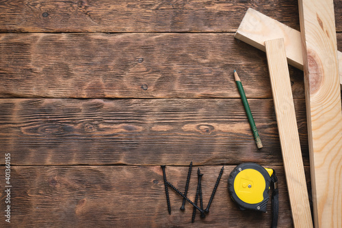 Fotótapéta Screws, meter, pencil and wooden bars on the carpenter workbench background flat lay