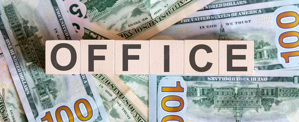 Concept words OFFICE on wooden blocks on a beautiful background from dollar bills. Concept words OFFICE on wooden blocks on a beautiful background from dollar bills.