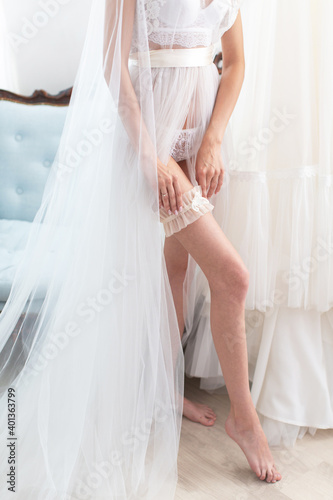 Close up of the bride holding a garter on her leg. Brides morning concept photo